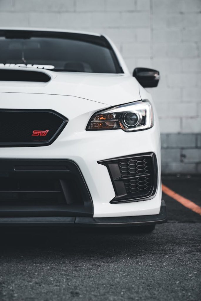 pexels-photo-22040010 Stylish white Subaru WRX with sleek headlight design, captured stationary in an urban setting.